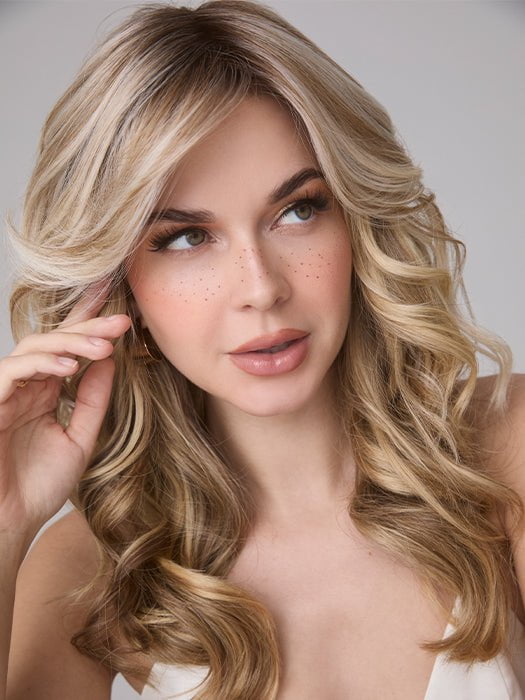 Model is wearing MEDIUM WAVY TP MONO by AMORE in color SEA SALT BLOND R | A perfect mixture of cool, icy-blond and warm-dark blond. The rich brown root tone enhances the modern appearance. 