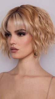 Model is wearing ROSANNA by RENE OF PARIS in color PEACHES AND CREAM | A vibrant peach blonde with creamy undertones and bright, face-framing cream highlights. Rich chocolate root adds depth.