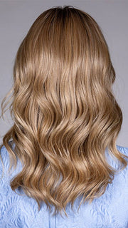 Model is wearing SWIFT in color CARAMEL TOFFEE BLONDE R | Caramel Toffee is a warm, dimensional shade blending medium brown with golden blonde and caramel highlights. Softly rooted for a natural, sun-kissed finish.