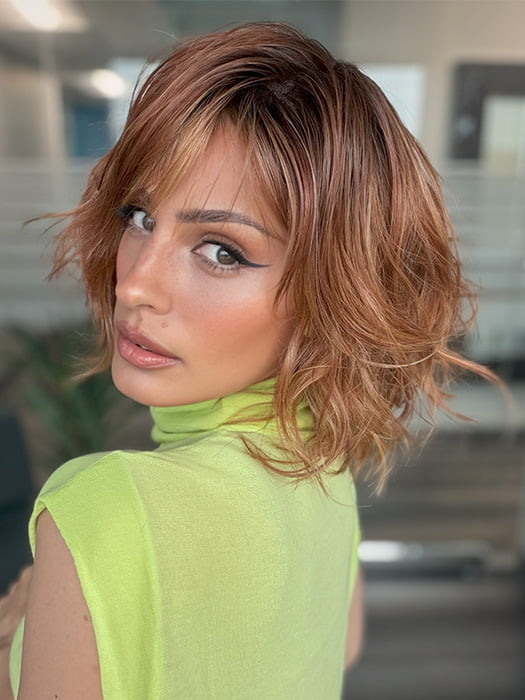 Model is wearing TERRA by AMORE in color RUSTY-SUNRISE-R | Dark brown roots transition into a deep auburn tone with light copper blonde highlights for depth and dimension.