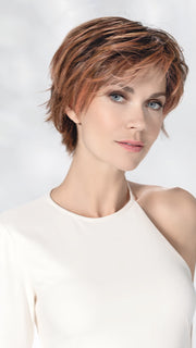 Model is wearing AVENUE SOFT by ELLEN WILLE in color ROSEWOOD LIGHTED | Medium Brown, Caramel, and Rose Gold blend with Highlights Throughout and Concentrated in the Front with Shaded Roots